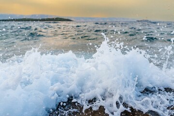 Scenic shot of the sea waves hitting the shore at sunset
