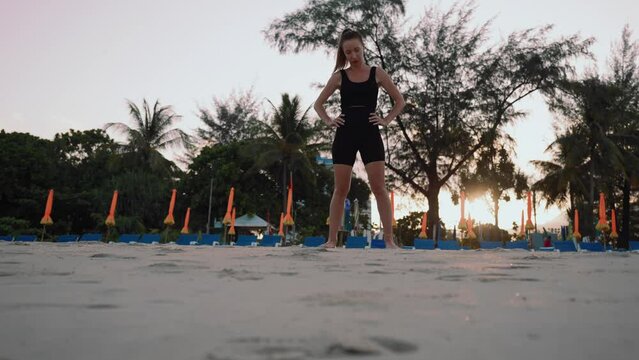 Barefooted woman doing yoga exercise lounge, warrior pose on sandy sea ocean beach at sunset. Female stretching legs. Body care, wellness, healthy lifestyle, sport people morning sporty concept.