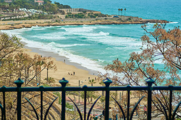 Quiet beach in Tarragona with gentle waves, golden sand and an artistic fence, ideal for promoting...