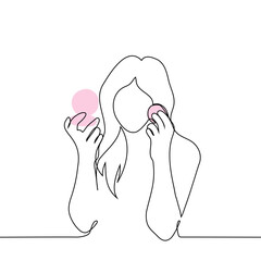 woman applies blush or powder to her face while looking into a small hand-held round mirror - one line art vector. concept long haired woman applying makeup
