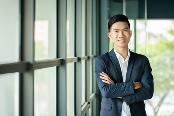 A modern-day manager stands with confidence among his team, arms crossed and a pleasant smile that radiates leadership and assurance.