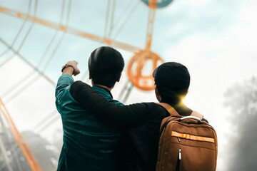 Man, holding his arm on the shoulder of a man pointing at a panorama wheel,the concept of friendship