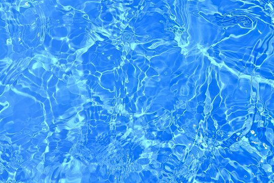 Close-Up of sunlight reflection on blue water surface. blue water texture for summer background