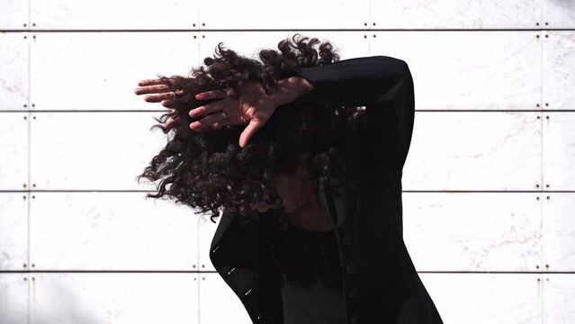 Caucasian Curly Woman Dancing In Front Of A White Wall