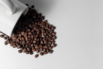 A Cup Of Coffee Beans Spilled On White Surface
