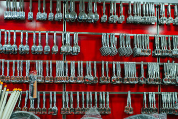 metal tongs ready for sale hanging on the wall in store, red background