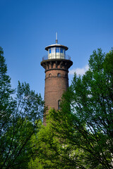 the historic helios lighthouse behind trees and against a blue sky