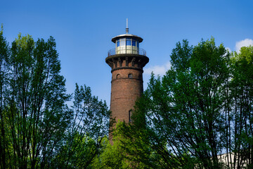 the historic helios lighthouse behind trees and against a blue sky