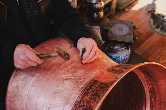 coppersmith working with decoration pattern on copper cauldron, coppersmith, who works in traditional handicrafts, shot from above