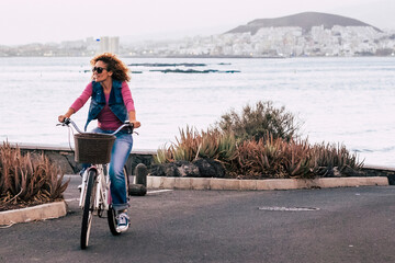 One young lady riding bike alone on the street with ocean coastline view. Outdoor leisure activity green transport woman. People and healthy lifestyle. Concept of tourist on vacation