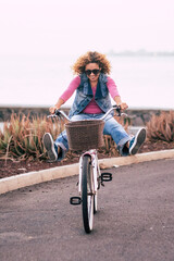 One young lady riding bike alone on the street with ocean coastline view. Outdoor leisure activity green transport woman. People and healthy lifestyle. Concept of tourist on vacation having fun