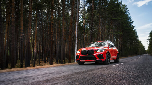 Seattle, Washington, USA April 7, 2024: The red updated BMW X5 m Competition car moves along the highway in the forest. Luxury SUV from a famous German brand. front view