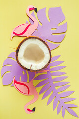Broken coconut, paper tropical leaves and flamingos on a light yellow background. - 782006654