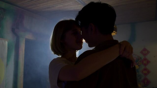 silhouette of young mixed race interracial lovers couple dancing and kissing in slow motion during first date