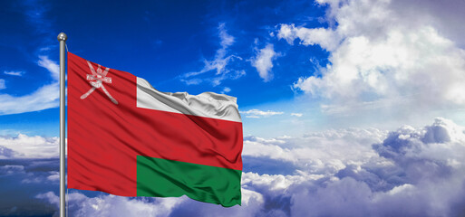 Oman national flag cloth fabric waving on beautiful Blue Sky Background.