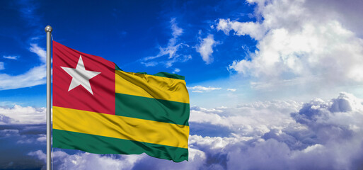 Togo national flag cloth fabric waving on beautiful Blue Sky Background.