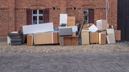 Pile of bulky waste with furniture on the side of the road in front of a house