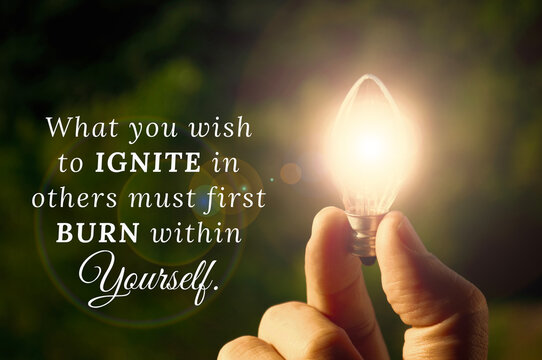 What you wish to ignite in others must first burn within yourself quote with hand holding shining bulb background. Inspirational quotes concept