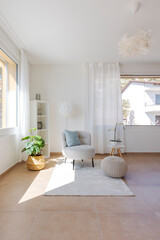 Detail of a living room corner with a small armchair with a coffee table and a pouf resting on the carpet. - 782011295