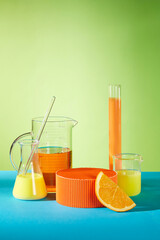 A group of lab equipments with orange and lemon color on green background, yellow liquid in an...
