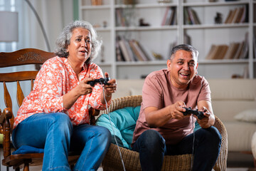Happy Indian asian mid age couple having fun, playing video game together - obrazy, fototapety, plakaty