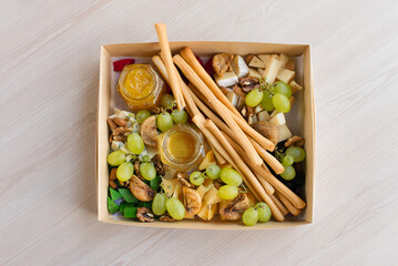 Set of traditional Italian breadsticks, delicious crispy grissini sticks, honey, grapes, cheese and figs. Catering box	