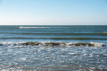 Fototapeta premium Detail of the waves of the Atlantic sea beating on the golden sand beach during the summer holidays in the province of Huelva, Spain.