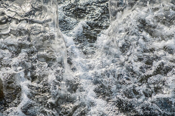 Detail of the splashes of water falling from the jet of a fountain on the surface. Frozen water movement. High speed. Horizontal.