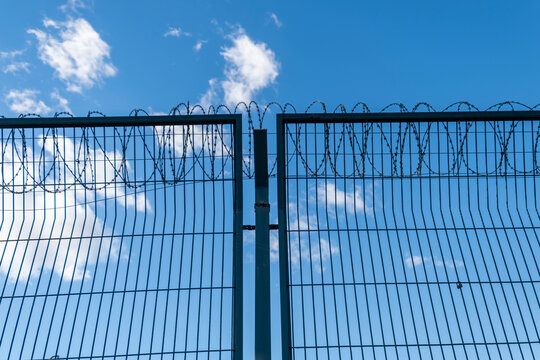 Concertina barb wire, heavy duty, metal fence. A prison, crime concept low angle shot. Horizontal, real photo.