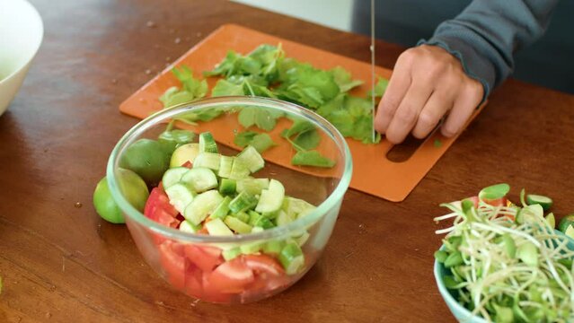 Person chopping vegetables beside a bowl, preparing ingredients for a dish