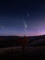 Falling meteors, evening landscape. Meteor shower over the hills. Bright fireballs in the sky, dreamy view.