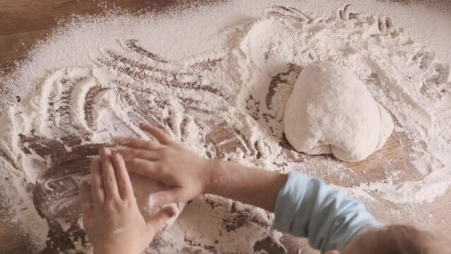 Little 5-year-old girl kneads dough in kitchen, mastering cooking skills, flour on countertop, joyful childhood, family teamwork and teaching children responsibility from young age