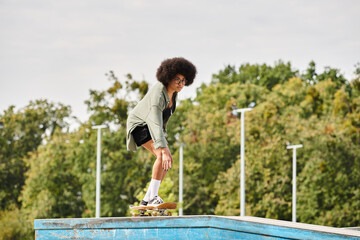 A young African American woman with curly hair gracefully rides her skateboard on a ramp at an...