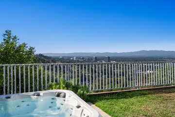 Hot tub sits on a lush green lawn near a wooden deck in Hidden Hills, CA