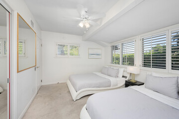 Fototapeta na wymiar Minimalistic white bedroom with two beds and windows in Hidden Hills, CA