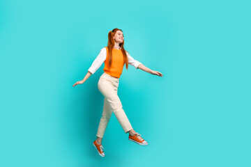 Fototapeta na wymiar Photo of optimistic positive cute girl wear orange trendy clothes fly air walk empty space isolated on aquamarine color background