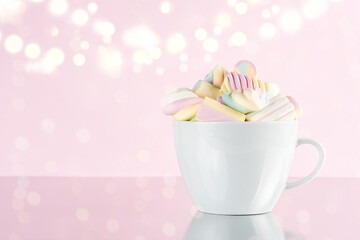 Marshmallows colorful chewy candy in a cup on pink bokeh background. Sweet holiday food concept.