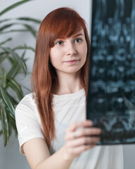 woman orthopedic doctor examines MRI, X-ray image. Rehabilitation specialist looks at MRI scan in...