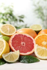 Different cut and whole citrus fruits on white table, closeup