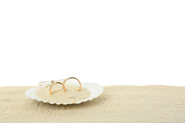 Honeymoon concept. Two golden rings in shell and sand isolated on white