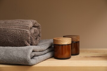 Soft towels and candles on wooden shelf indoors, closeup
