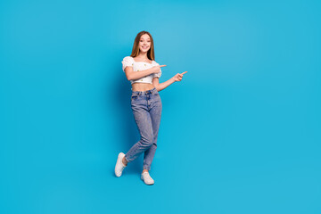 Fototapeta na wymiar Full length portrait of lovely girl indicate fingers empty space wear top isolated on blue color background