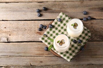 Composition with tasty yogurt in glasses and blueberries on wooden table, top view. Space for text