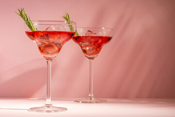 Refreshing cocktail with rosemary in a glass on a bright background. Summer party concept.