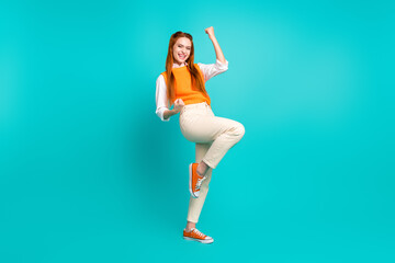 Photo of lovely pretty cheerful girl wear trendy orange outfit raised hands yes hooray isolated on cyan color background