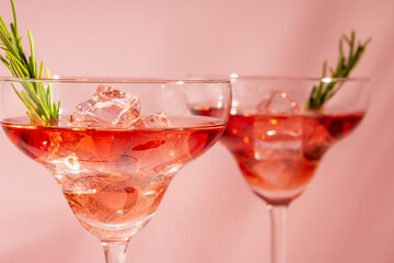 Refreshing cocktail with rosemary in a glass on a bright background. Summer party concept.