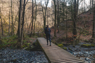 Woman walks along a wooden path in the Wallonia region of Belgium. Exploring the wilderness at Reinhardstein Castle in Belgium