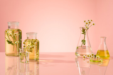 Transparent glasses beaker containing yellow fluid extract from chamomile flower and decorated with...