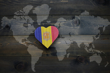 wooden heart with national flag of andorra near world map on the wooden background. - obrazy, fototapety, plakaty