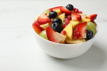 Tasty fruit salad in bowl on white table, closeup